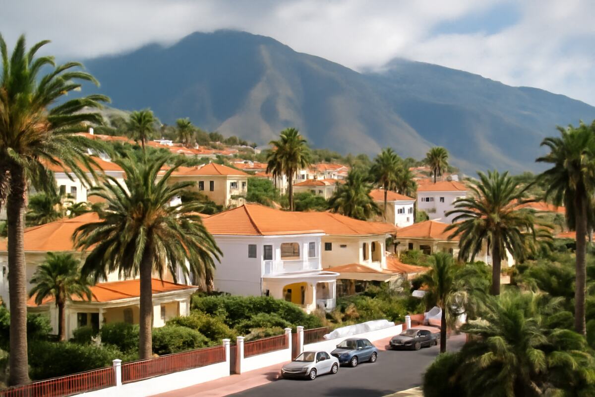 Typisches Wohngebiet auf Teneriffa mit Palmen und Bergen.